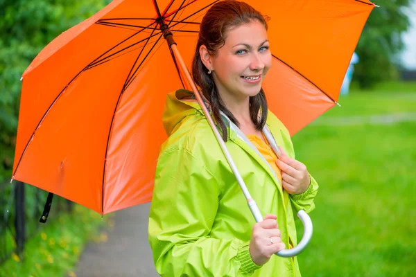 Beautiful young brunette woman with an orange umbrella closeup — Stock Photo, Image