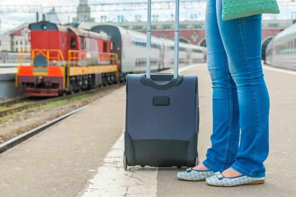 Koffer und Frauenfüße warten am Bahnhof auf einen Zug — Stockfoto