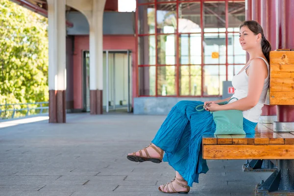 Meisje wacht op de trein op het station zittend op een bankje — Stockfoto