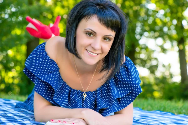 Girl in blue dress lying on the blanket and smiling — Stock Photo, Image