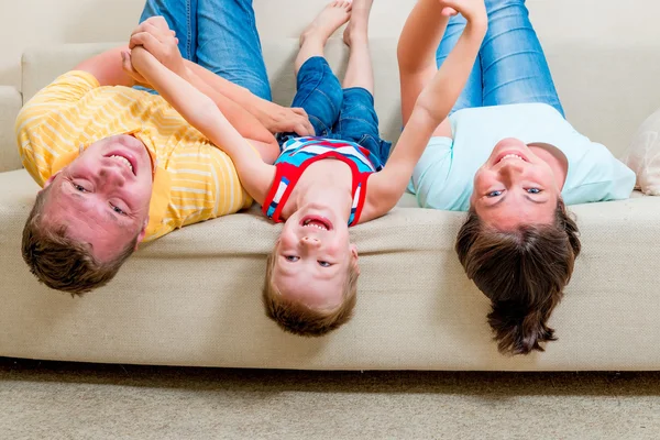 Familia feliz con un niño en un sofá en la sala de estar — Foto de Stock