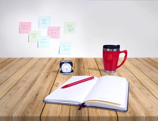 Composition of different promo products with rich colors -Thermo mugs, pen, silver table office clock, open notebook,On wooden desk grey and background grey wall and note paper.