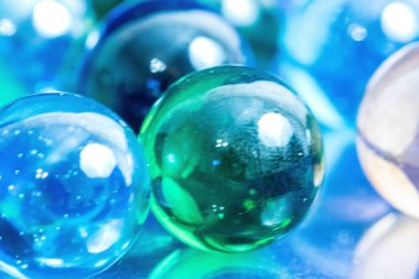 Bulanık bir arka planda cam toplar. Sığ bir alan derinliğine ateş ediyorlar. Mavi-yeşil cam