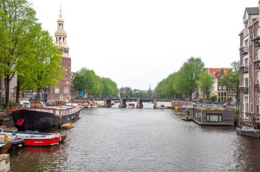 AMSTERDAM, NETHERLANDS. Haziran 06, 2021. Tipik Hollandalı evleri, köprüleri ve Chanel 'i olan Amsterdam' ın güzel manzarası. Barajdaki küçük tekneler