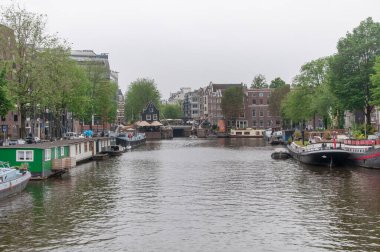 AMSTERDAM, NETHERLANDS. Haziran 06, 2021. Tipik Hollandalı evleri, köprüleri ve Chanel 'i olan Amsterdam' ın güzel manzarası. Barajdaki küçük tekneler