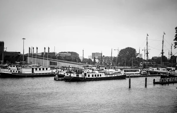 stock image AMSTERDAM, NETHERLANDS. JUNE 06, 2021. Beautiful view to a shipping channel and bridges. Black and white photography. Small boats, ships and barges in the port. Black and white photography.