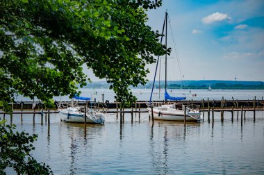 BOHMTE, ALMANLIK. 27 Haziran 2021 Dammer Doğal Parkı. Göl manzarası, tekneler, yatlar, sahilde dinlenen rıhtım insanları.