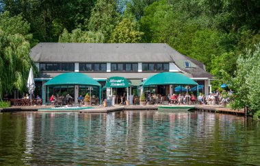 Harcama, Almanca. 20 Haziran 2021 'de. Hoocker Mağribi Çiftliği. Göl manzarası, setin üzerindeki kafede dinlenen insanlar..