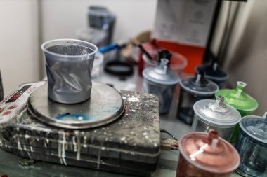unrecognizable car painter, making the right mix for the color of the car with the computer and the scale in the paint booth of his workshop