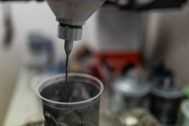 unrecognizable car painter, making the right mix for the color of the car with the computer and the scale in the paint booth of his workshop