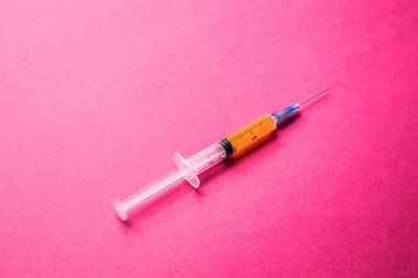 Şırıngaları kapatın ve pembe arka planda keskin iğneler