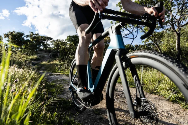 young male cyclist riding his gravel e-bike on an outdoor trail at sunset, side view, horizontal photography