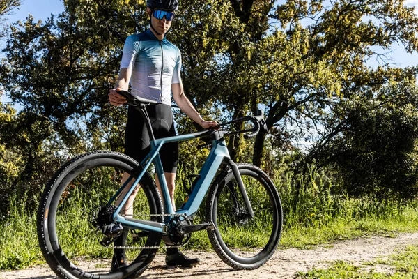 young male cyclist ready with his gravel e-bike on a trail