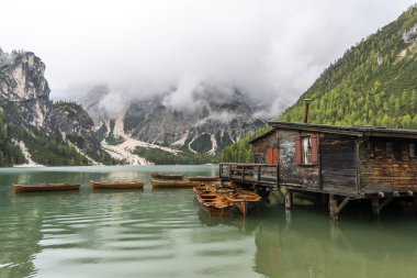 Dolomitlerdeki Pragser Wildsee Gölü. İtalya 'da sonbaharda bir tekne, dağ ve orman zinciri..