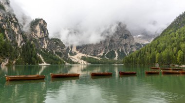 Dolomitlerdeki Pragser Wildsee Gölü. İtalya 'da sonbaharda bir tekne, dağ ve orman zinciri..