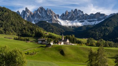 Dolomitlerdeki Santa Magdalena Kilisesi 'nin arka bahçesinde ünlü Geisler dağları sonbaharda günbatımında çekilmiştir..