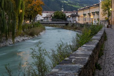 Brixen, Italy - October 9, 2020: City centre of Brixen at night with the river Eisack, Isarco, church and bridge. clipart