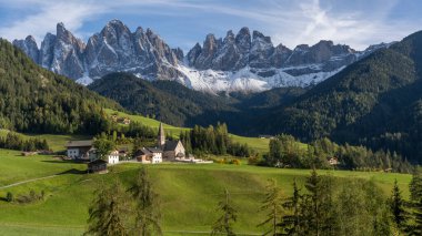 Dolomitlerdeki Santa Magdalena Kilisesi 'nin arka bahçesinde ünlü Geisler dağları sonbaharda günbatımında çekilmiştir..