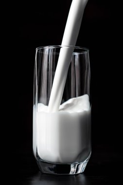 Siyah arka plan üzerine bir bardak milkg dökme