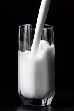 Siyah arka plan üzerine bir bardak milkg dökme