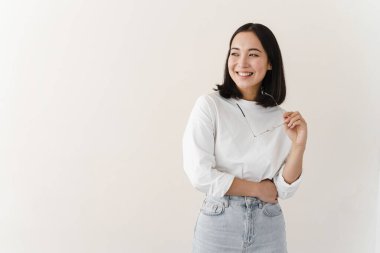 Boş bir duvarda gülümseyen sevimli kız. Elinde gözlük tutan genç bir kadın. Reklam için yer, kopyalama alanı.