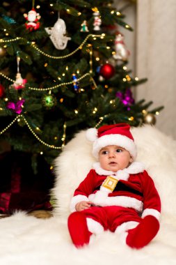 Noel Baba olarak ağacın altında giyinmiş bir çocuk