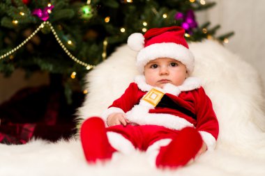 Noel Baba olarak ağacın altında giyinmiş bir çocuk