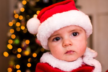 Noel Baba olarak ağacın altında giyinmiş bir çocuk