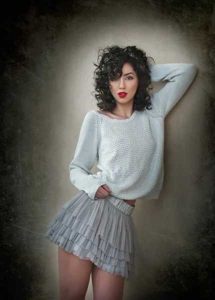 Charmante jonge curly brunette vrouw in kant korte rok en witte blouse, leunend tegen muur. Sexy prachtige jonge vrouw met lange benen in de buurt van de muur. Portret van sensuele meisje met wulpse mond poseren — Stockfoto