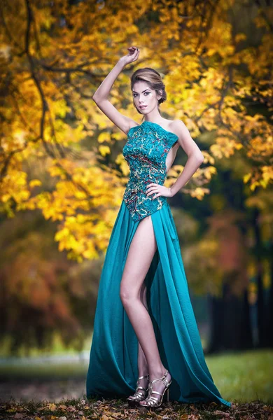 Mujer joven hermosa de moda en vestido azul posando bosque oxidado al aire libre en el fondo. Chica atractiva con vestido elegante posando en el parque otoñal. Lujosa dama elegante en azul, concepto otoñal —  Fotos de Stock