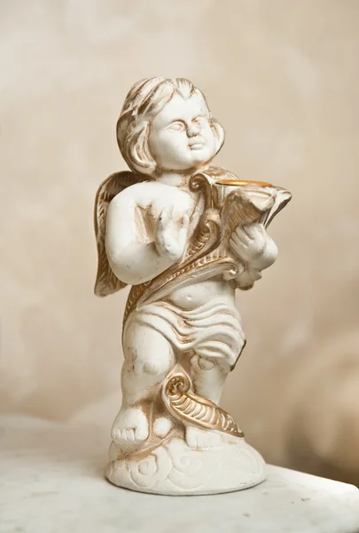 Ange avec lyre, ornement. Ornement doré. Ange vintage. Ange en céramique jouant de la harpe. Statette de Cupidon sur table en marbre . — Photo