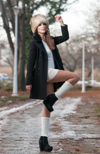 Ritratto di giovane bella donna, ripresa all'aperto nel paesaggio invernale. Sensuale ragazza bruna con cappotto e berretto di pelliccia in posa in un parco coperto di neve. Donna alla moda in un giorno freddo . — Foto Stock