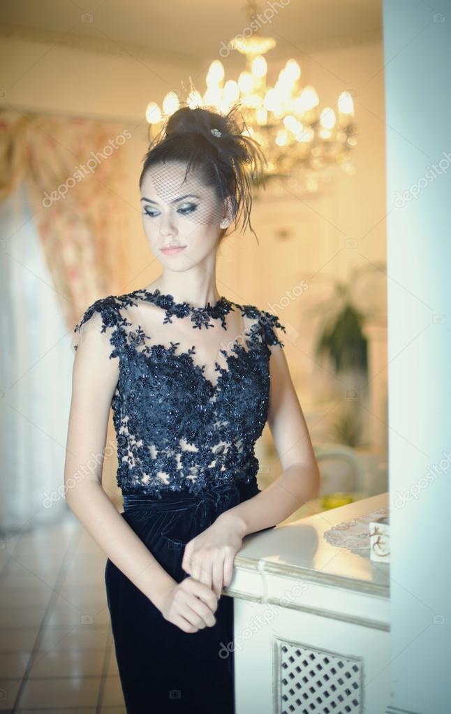 Beautiful brunette lady in elegant black lace dress posing in a
