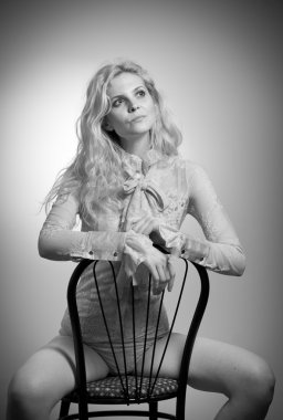 Kışkırtıcı, atış studio iskemlede zarif çıplak bluz çekici sarı saçlar modelinde ile. Uzun kollu ve şerit üzerinde sandalye ile klasik bluz içinde bir şehvetli sarışın kadın moda portre