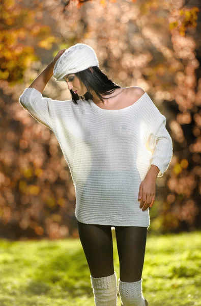 Beautiful sexy girl in white posing in park in autumn day. Beautiful elegant woman with white cap in autumnal park. Young pretty brunette woman with leggings and long legs in the forest — Stock Photo, Image