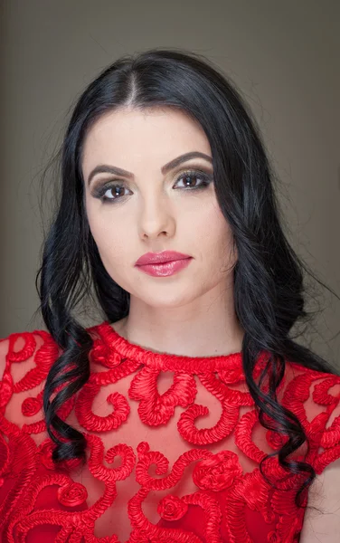 Kapsel en make-up - mooie vrouwelijke kunst portret met mooie ogen. Elegantie. Echte natuurlijke lange haren brunette in studio. Portret van een aantrekkelijke vrouw met rode lippen in rode kant blouse — Stockfoto