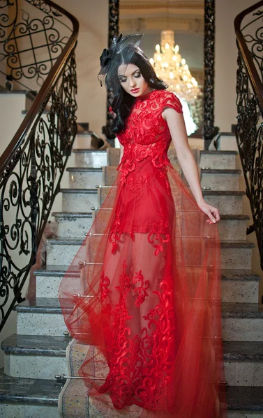 Krásná dívka v dlouhé červené šaty pózuje v ročníku scéně. mladá krásná žena nosí červené šaty ve starém hotelu. smyslná elegantní mladá žena v červené dlouhé šaty krytý shot. — Stock fotografie