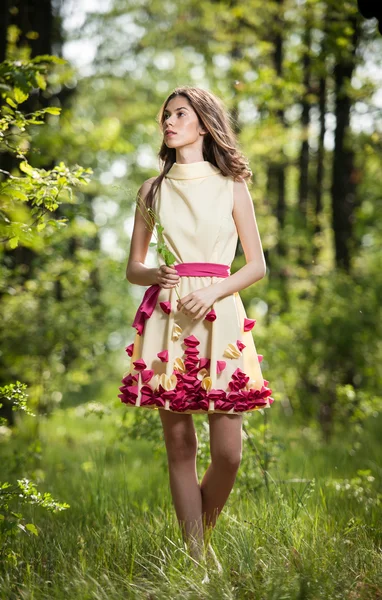Joven chica hermosa en un vestido amarillo en el bosque. Retrato de una mujer romántica en el bosque de hadas. Impresionante modelo adolescente de moda en el prado de verano, tiro al aire libre. Linda morena pelo largo femenino . — Foto de Stock