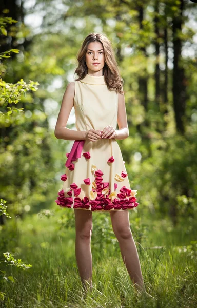 Ung vacker flicka i en gul klänning i skogen. Porträtt av romantiska kvinnan i fairy forest. Fantastisk fashionabla teenage modell i Sommaräng, utomhus skott. Söt brunett långt hår kvinna. — Stockfoto