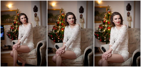 Hermosa mujer sexy con árbol de Navidad en el fondo sentado en una silla elegante en un paisaje acogedor. Retrato de niña posando bonita con vestido blanco corto y ajustado. Atractiva morena femenina, tiro de interior . —  Fotos de Stock