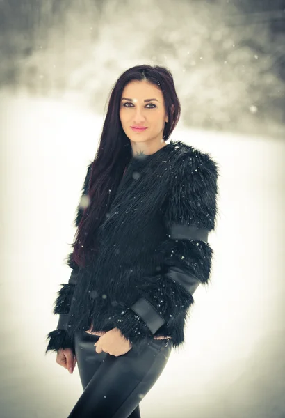 Vista di felice ragazza bruna che gioca con la neve nel paesaggio invernale. Bella giovane femmina su sfondo invernale. Attraente giovane donna in caldi vestiti morbidi all'aperto in una giornata invernale — Foto Stock