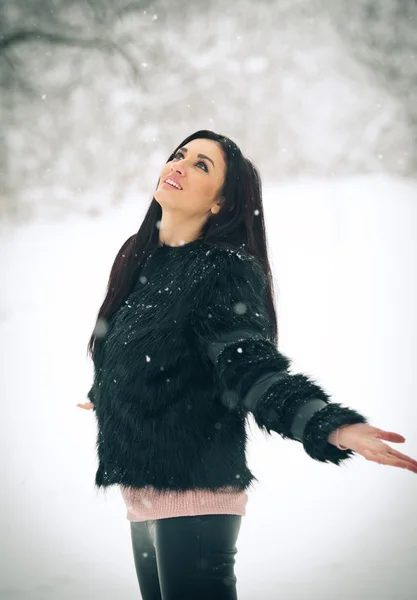 快乐的黑发女孩玩雪冬季景观中的视图。美丽的年轻女性在冬天背景。年轻漂亮的女人，在室外的一个冬日温暖柔软的衣服 — 图库照片