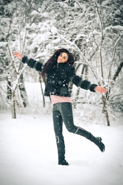 Vista da menina morena feliz brincando com a neve na paisagem de inverno. Linda jovem fêmea no fundo do inverno. Jovem atraente em roupas macias quentes ao ar livre em um dia de inverno — Fotografia de Stock