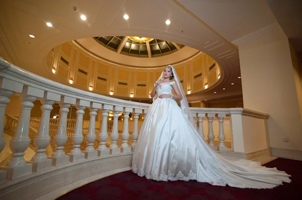 Jonge mooie luxe vrouw in trouwjurk poseren in luxe interieur. Bruid met enorme trouwjurk in majestueus herenhuis. Verleidelijke blonde bruid met prachtige jurk en lange dally poseren — Stockfoto