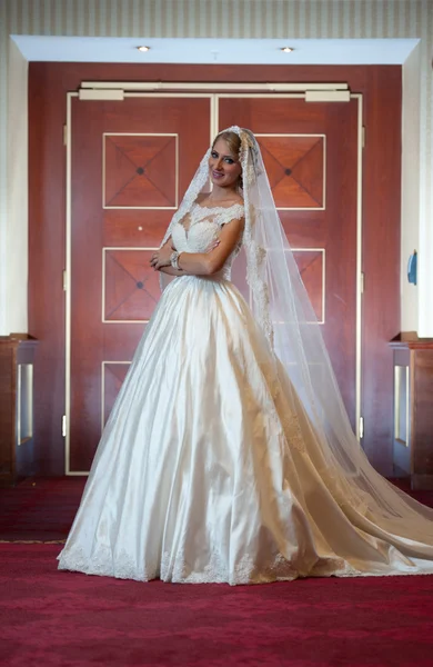 Jonge mooie luxe vrouw in trouwjurk poseren in luxe interieur. Prachtige elegante bruid met lange sluier. Portret van de volledige lengte van verleidelijke blonde bruid met modieuze jurk, binnen schot — Stockfoto