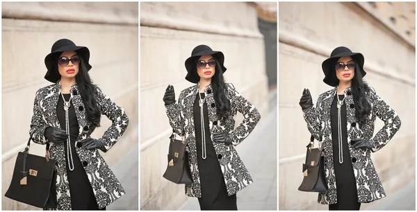 Atractiva joven en una foto de moda de invierno. Hermosa chica joven de moda en negro posando en la avenida. Elegante morena con sombrero, gafas de sol y bolso en el paisaje urbano . —  Fotos de Stock