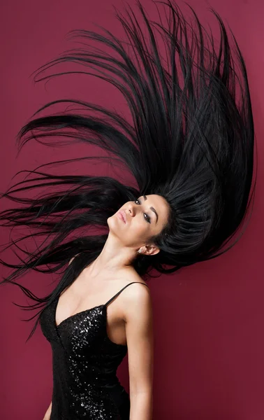 Mulher morena atraente em um preto brincando com seu cabelo longo no fundo roxo. Retrato de arte feminina de cabelo comprido, estúdio. Menina cabelo escuro natural genuíno, tiro em movimento. Slim jovem mulher posando interior — Fotografia de Stock