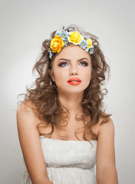 Porträt eines schönen Mädchens im Studio mit gelben Rosen im Haar und nackten Schultern. sexy junge Frau mit professionellem Make-up und leuchtenden Blumen. Kreative Frisur und Make-up, Studioaufnahmen — Stockfoto