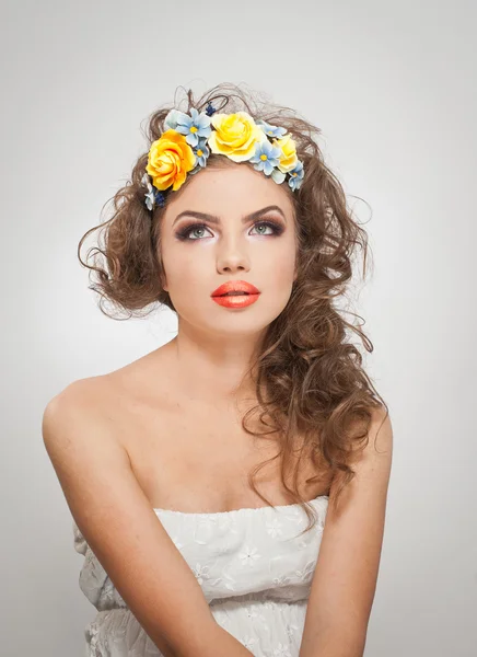 Portrait de belle fille en studio avec des roses jaunes dans les cheveux et les épaules nues. Jeune femme sexy avec un maquillage professionnel et des fleurs lumineuses. Coiffure créative et maquillage, plan studio — Photo