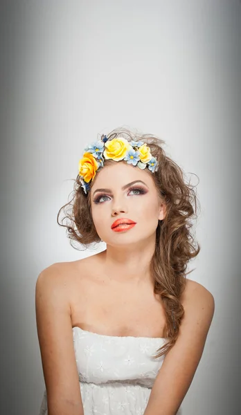 Portrait of beautiful girl in studio with yellow roses in her hair and naked shoulders. Sexy young woman with professional makeup and bright flowers. Creative hairstyle and makeup, studio shot — Stock Photo, Image